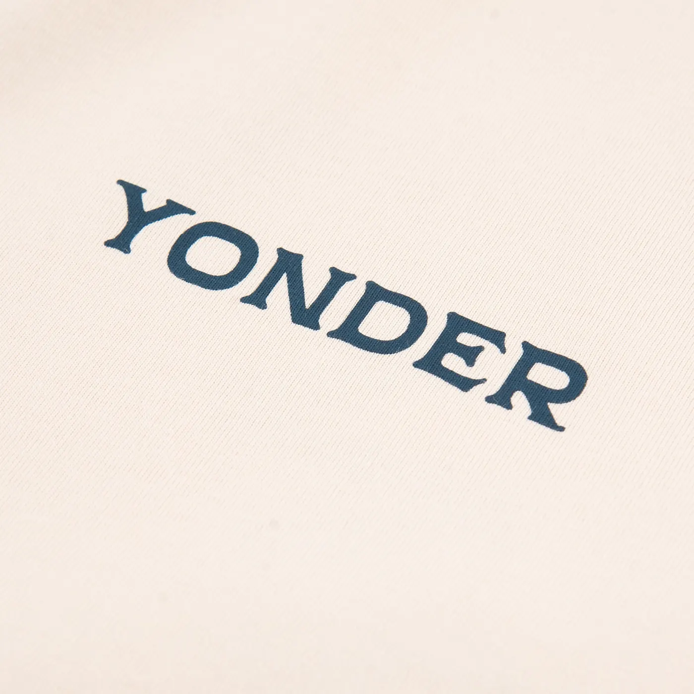 Close-up of a navy YONDER screen print on a cream T-shirt