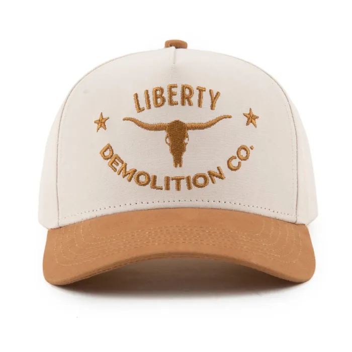 Five-panel hat, cream crown with tan suede brim, raised tan embroidery of a longhorn skull