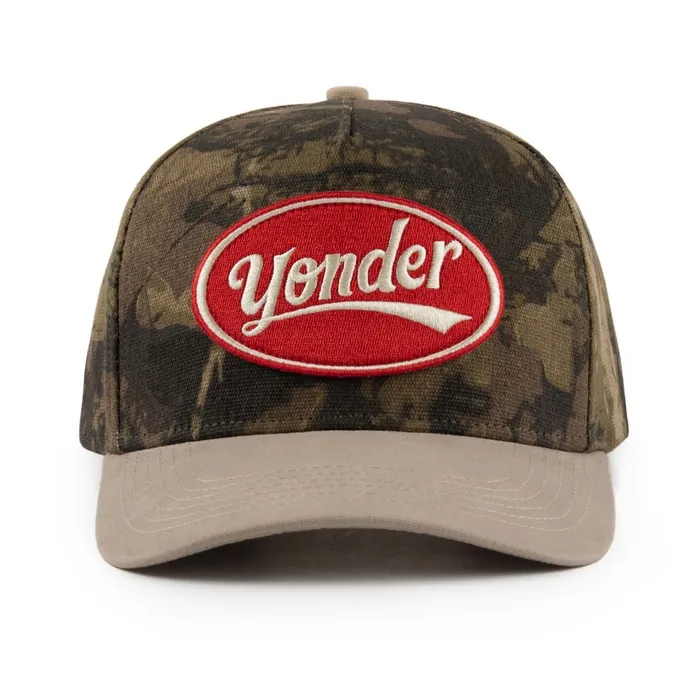 Five-panel camouflage hat with a khaki brim, red oval woven patch, red arched embroidery on the back
