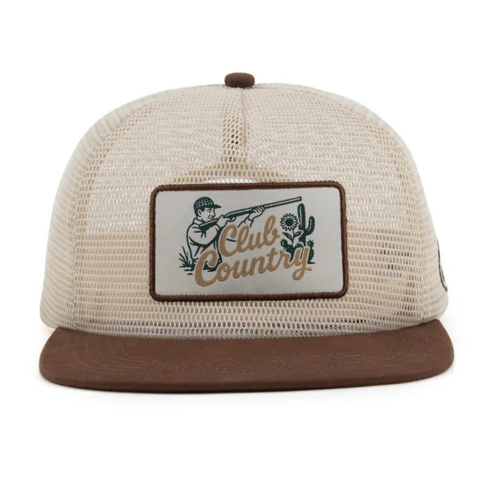 Five-panel mesh-back hat, cream mesh with a flat brown brim, woven rectangular patch of a shooter and cactus, circular monogram on the side, printed taping inside