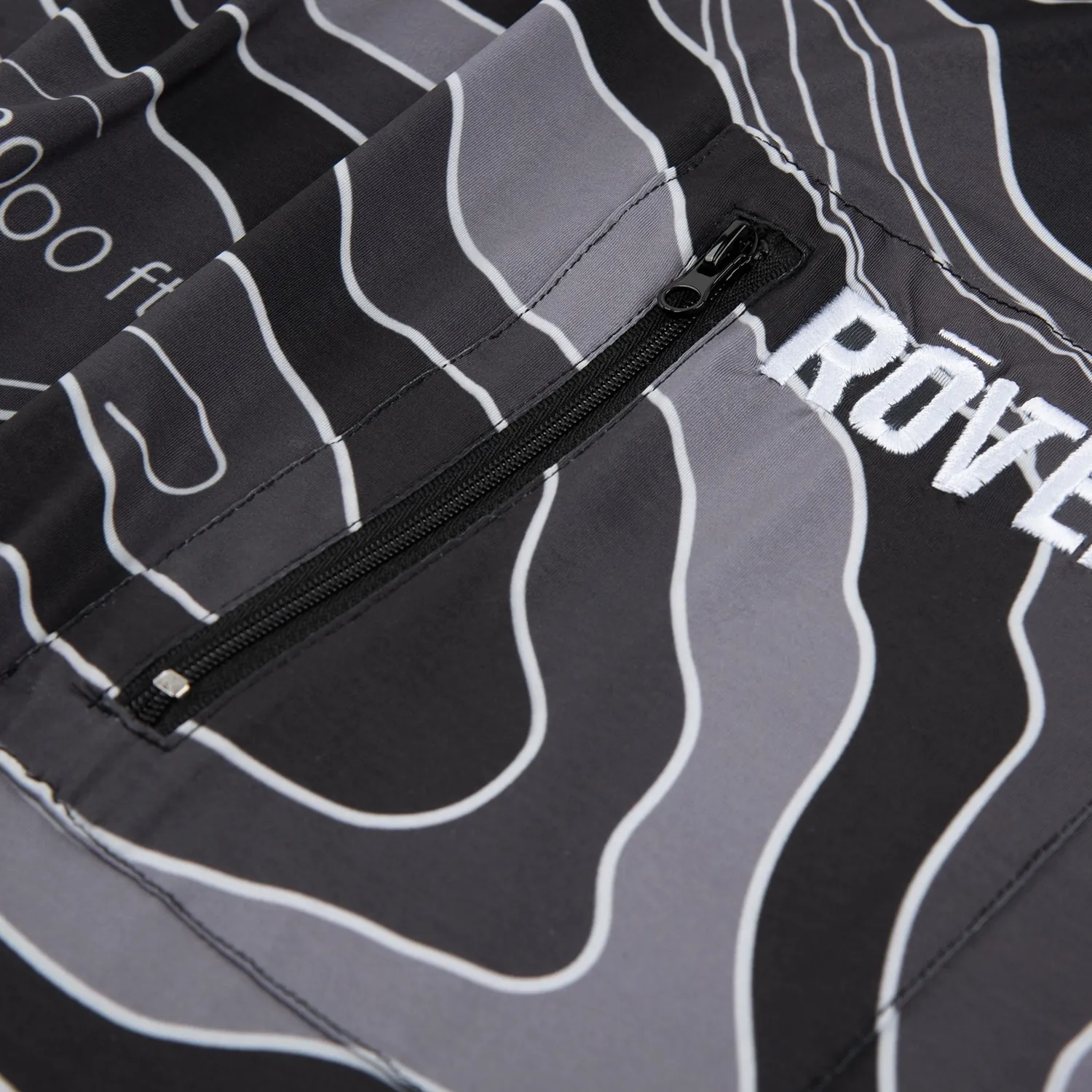 Close-up of white embroidered lettering beside a zip pocket on a printed jacket